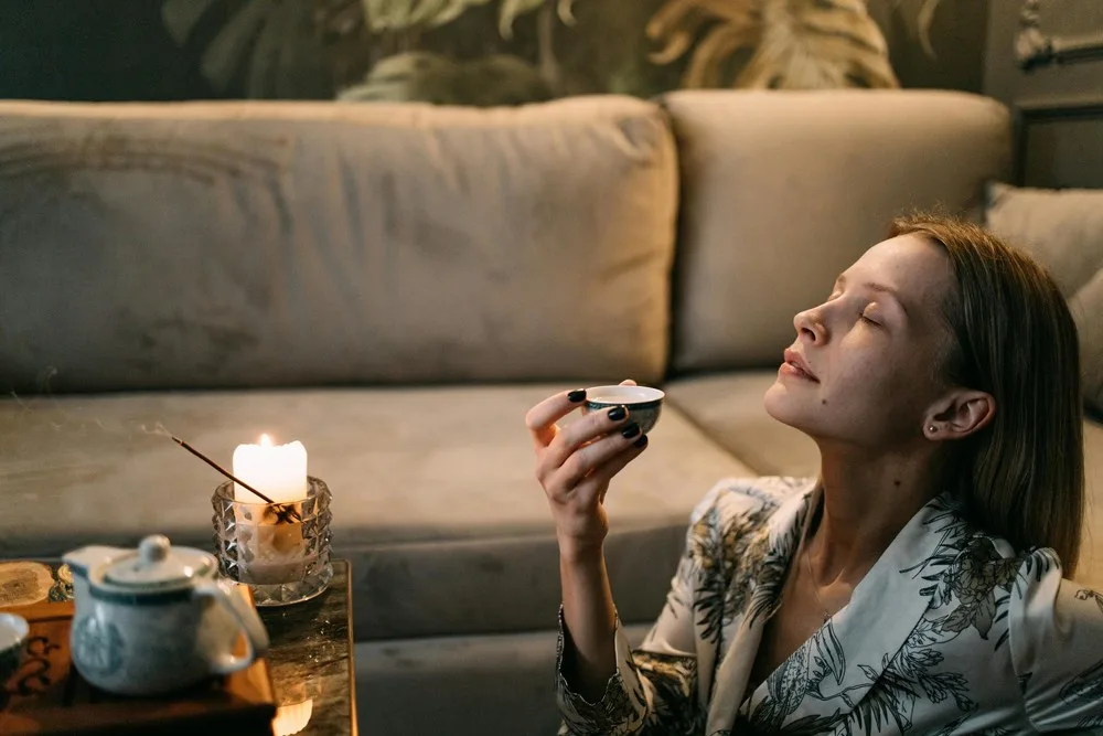 Une femme épanouie boit une tasse de thé dans une ambiance zen